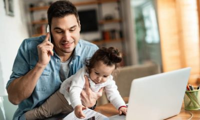 Young working father talking on the phone while babysitting his playful daughter at home | MIT Prof: Good Luck Getting WFH Employees Back to the Office | featured