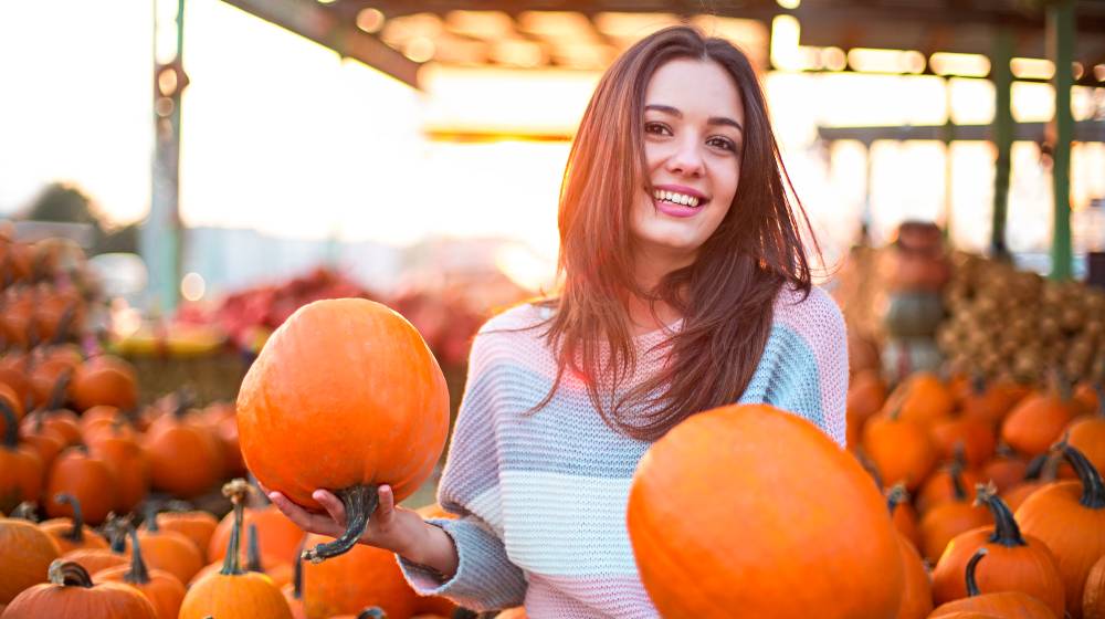 Fashionable beautiful young girl at the autumn pumpkin patch background | How Does The Stock Market Perform During Thanksgiving Week? | featured