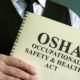 OSHA Occupational Safety & Health Act in the hands | OSHA Suspends Biden’s Large Employer Vaccine Mandate | featured