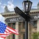 Wall Street signboard and stock exchange building on background | US Stock Market Posts New Record Highs On Strong Retail Earnings | featured