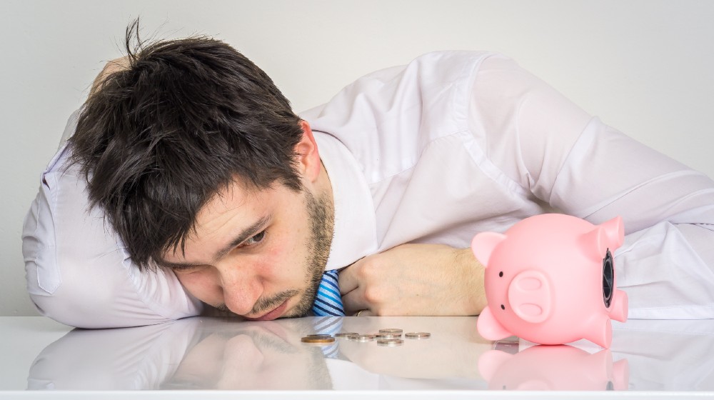 Young worried man has empty piggy money bank | Get Started In Investing With No Money | featured