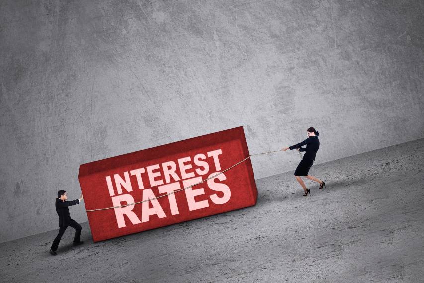 Business people trying to get a block with interest rates word on it | Interest Rates