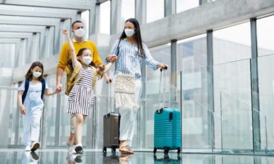 Family with two children going on holiday, wearing face masks at the airport | New COVID Rules On International Travelers Will Start Monday | featured