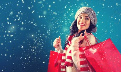Happy young woman holding shopping bags in a snowy night | Despite Omicron, US Holiday Sales up by 8.5% This Year vs Last Year | featured