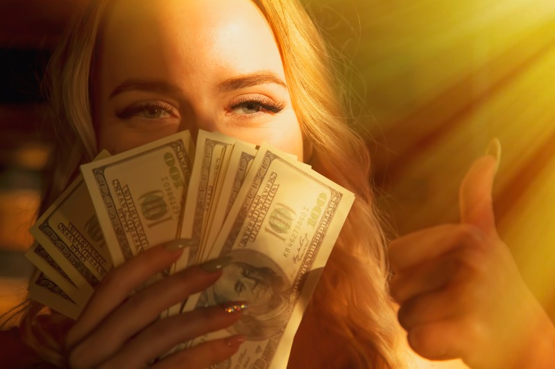 Beautiful woman with US Dollar bills making Ok gesture | Can Money Buy Happiness
