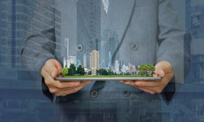 Double exposure with businessman holding tablet and city model in hands | Investors Are Buying Virtual Land Using Millions of Real Money | featured