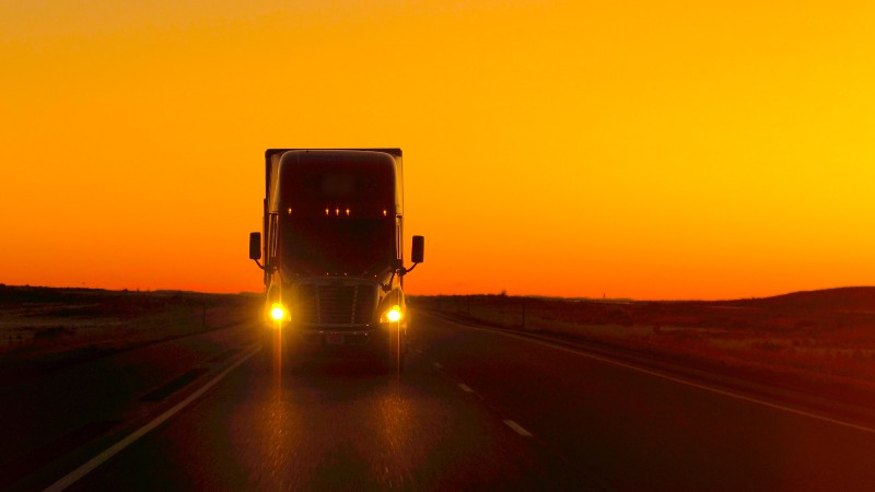 Semi truck driving and hauling goods on empty highway | Semi Trucks