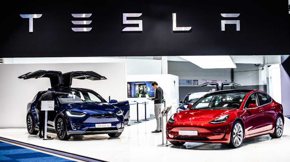 metallic red Tesla Model 3 and blue Tesla model X at Brussels Motor Show | Tesla Opens Xinjiang Showroom Despite Genocide Fears In Area | featured
