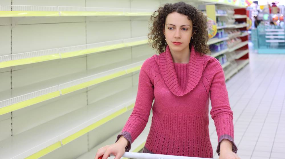 young woman with cart in shop with empty shelves | 4 Reasons Why Empty Store Shelves Are Everywhere | featured