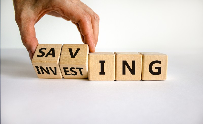 Saving or investing symbol. Businessman turns cubes and changes the word 'investing' to 'saving' | Everything You Need to Know About Investing