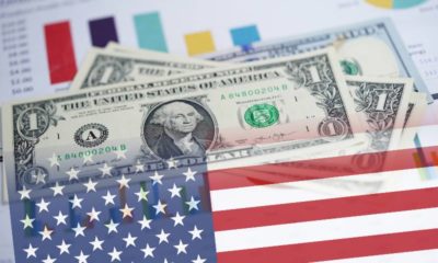 US-dollar-banknotes-money-on-chart-graph-spreadsheet-paper-with-USA-America-Flag-US-Economy-ss.jpg