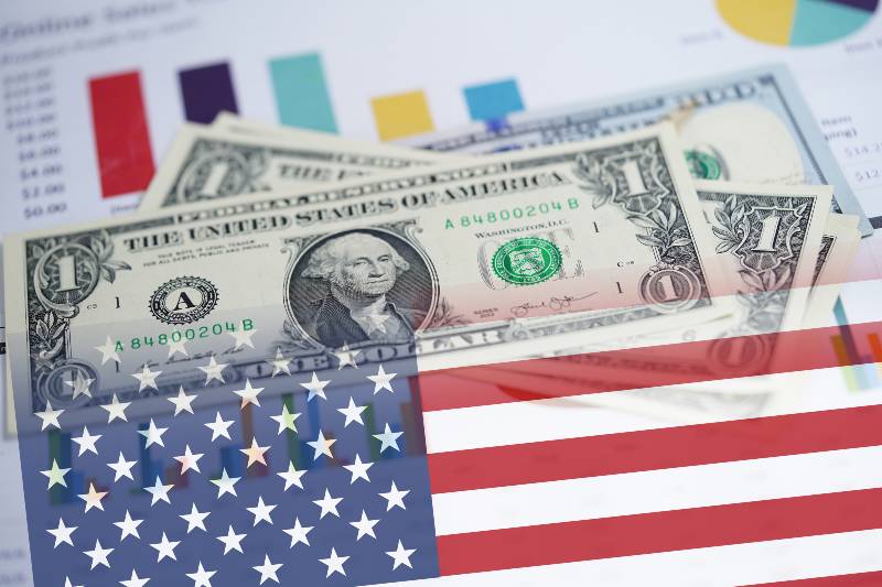 US dollar banknotes money on chart graph spreadsheet paper with USA America Flag | 2021 Was a Miracle Year for the US Economy | featured
