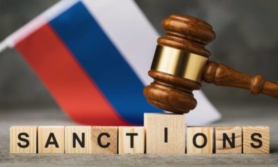 judge's gavel, wooden cubes with the text on the background of the Russian flag | Will Economic Sanctions Work Against Russia This Time? | featured
