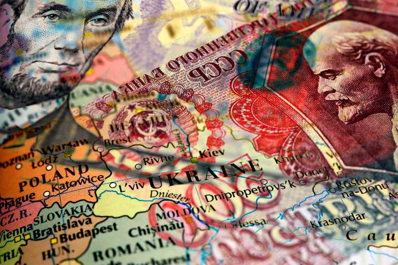 Close up of a 5 US dollar bill and Russian ruble banknote on top of a map of Ukraine | Isolating Russia One Business At A Time