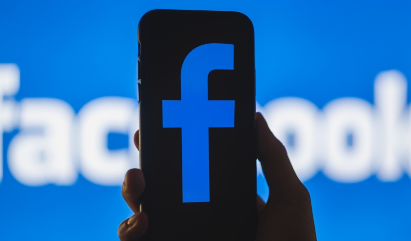 Facebook logo on the smartphone screen in hand-Less Time on Facebook-SS-Featured