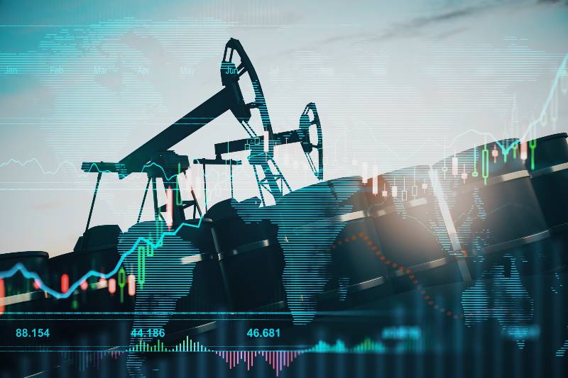 Oil pumping machinery in operation with barrels and digital screen with world map and financial chart | World Oil Prices Fall Below $100