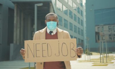 Portrait young african american man wear masks holding poster cardboard with Crisis | Latest Jobless Rate Totals 214,000, Lower Than Expected | featured
