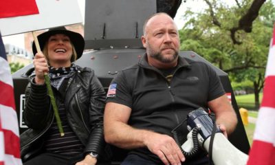 Alex Jones, with his wife Erika Wulff Jones, sits in the bed of an armored truck | InfoWars Files for Bankruptcy As Alex Jones Faces Legal Costs | featured