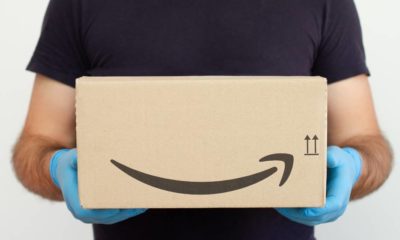 Amazon Delivery. Delivery man holding cardboard boxes in medical rubber gloves | LinkedIn Says Amazon Is The Best Company To Work for in 2022 | featured