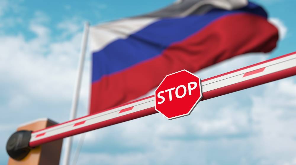 Barrier gate being closed with flag of Russia as a background | US Issues More Sanctions, Hopes To Crush Russia Further | featured