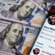 Elon Musk's Twitter account page on the smartphone which is is placed on the pile of dollar banknotes | Board Agrees to Elon Musk’s $44B Twitter Buyout Offer | featured