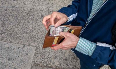 Looking down at a man with open wallet ready to spend some US cash | Why Is Inflation Still High? Here Are 3 Reasons Why | featured
