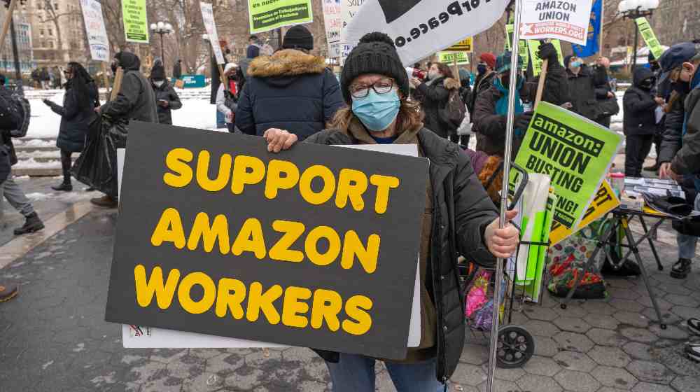 Protestors hold signs and march on a picket line across from Amazon's Whole Foods Market | Amazon Objects To Staten Island Union Election Victory | featured