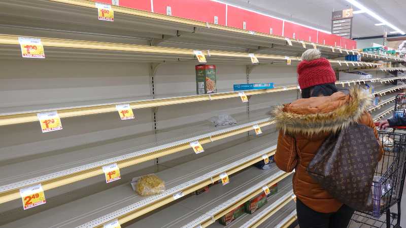 A shopper in front of empty pasta shelves | empty store shelves