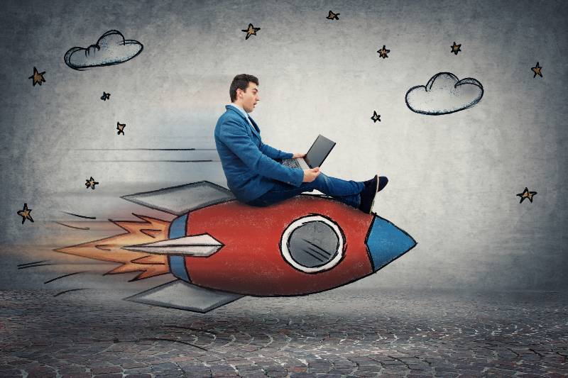 Amazed young businessman flying on a fast rocket looking at his laptop monitor | How to Skyrocket Your Net Worth By Building an Amazing Network with Jordan Harbinger