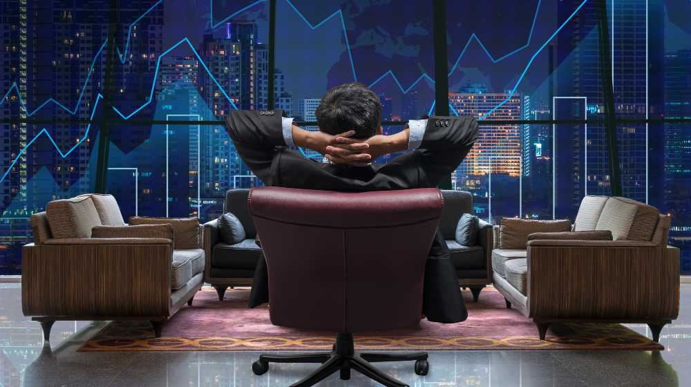 Back view of sitting businessman who is looking at Trading graph | CEOs, Corporate Insiders Sell Off $69B Worth Of Stock In 2021 | featured