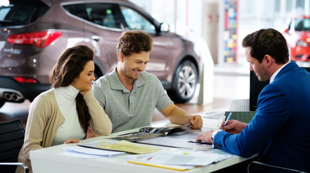 Beautiful-young-couple-reading-a-booklet-at-the-dealership-showroom-Car-Dealers-SS-Featured.jpg