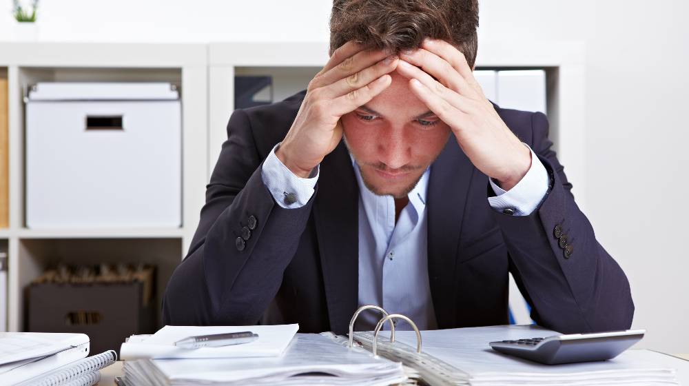 Business man in office with burnout syndrome at desk | Hold On To Your Portfolios Despite Russia-Ukraine Volatility | featured