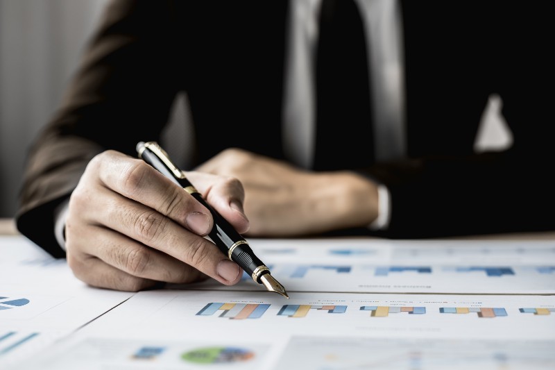 Businessman sits in a private office at his company and is reviewing company financial documents | Corporate Finance Law