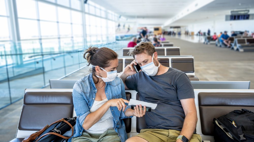 COVID-19 worldwide borders closures. Couple with face mask stuck in airport terminal after being denied entry to other countries-Coronavirus State Restrictions-ss-featured