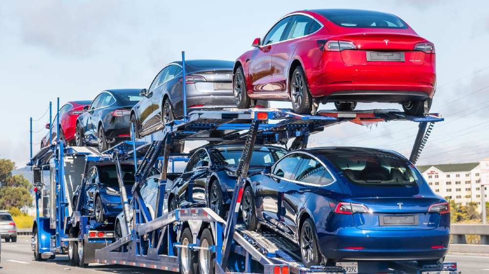 Car transporter carries Tesla Model 3 new vehicles on a freeway in San Francisco bay area-Tesla Stocks-ss-featured
