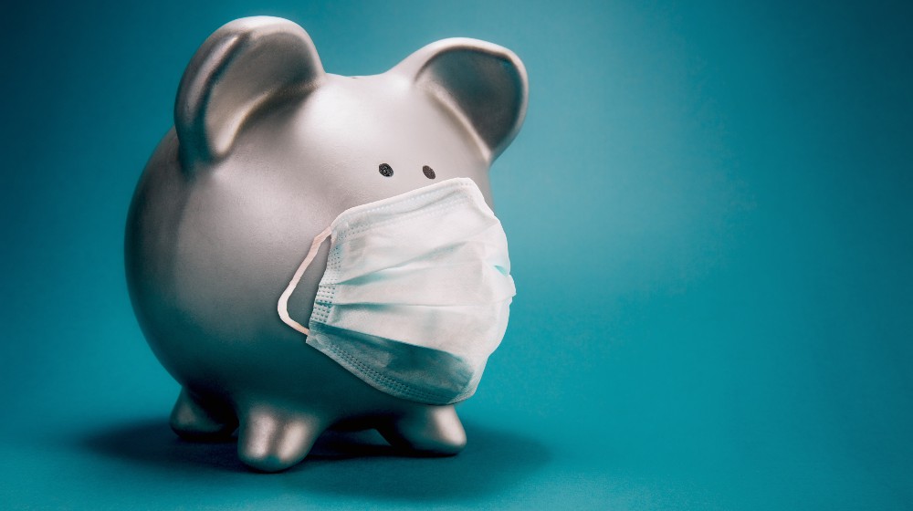 Close up of piggy bank, wearing protective face mask | The Biden Administration’s COVID Funding Is Nearly Out | featured