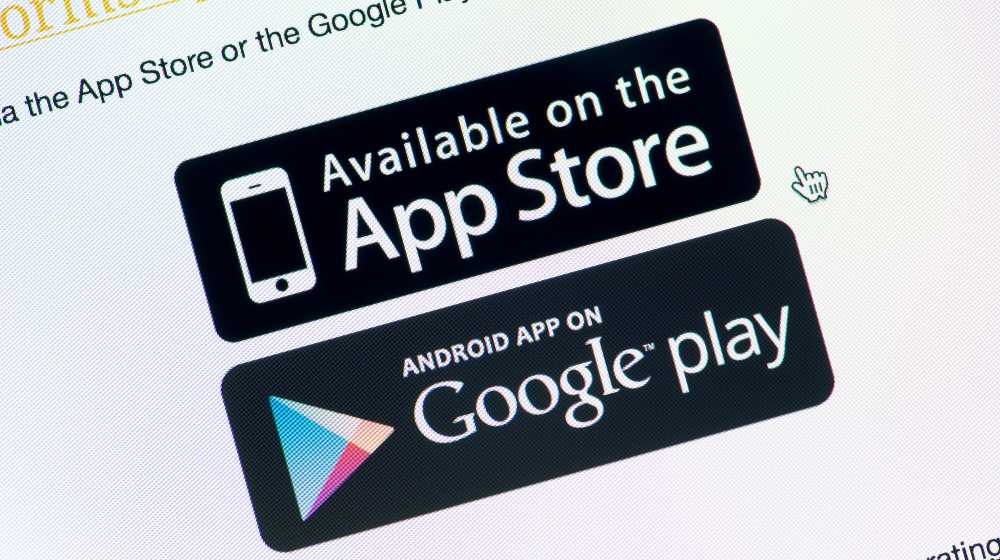 Close-up shot of monitor screen with App Store and Google Play download buttons | South Korea Wants to Ban Apple and Google’s Exclusive Stores | featured