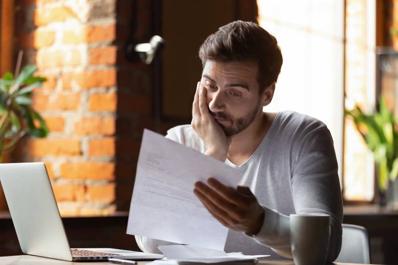 Confused frustrated young man reading letter in cafe, debt notification, bad financial report | How to KEEP Yourself Out of Debt #467