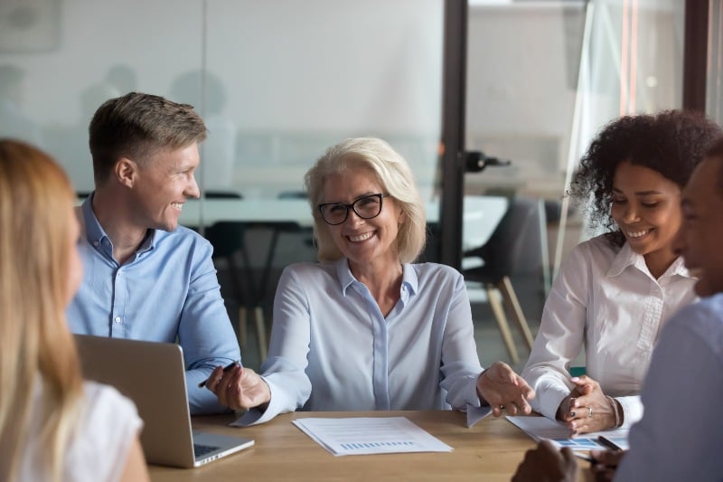 Different people young and aged multinational employees sitting around table in conference-age-Ss