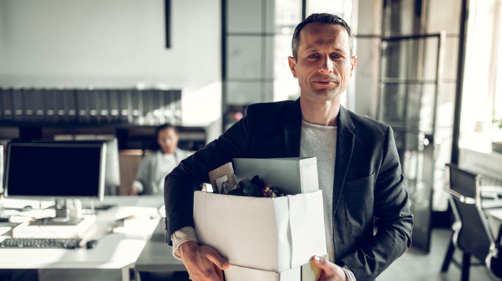 Economist leaving office. Handsome economist leaving the office taking his box with different things-ss-featured