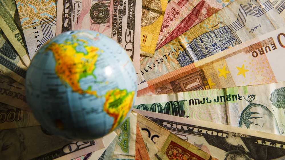 Globe map sign over many american dollar bank notes and bills of different states | 136 Countries Agree to Implement 15% Global Corporate Tax | featured