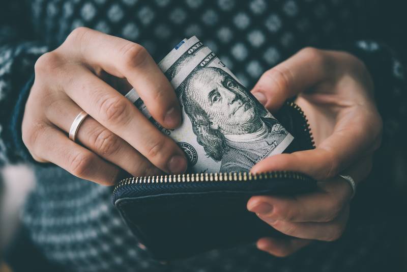 Hands holding us dollar bills and small money pouch | private money