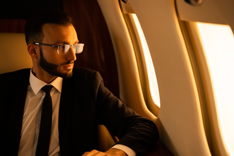 Handsome businessman wearing elegant suit flying on exclusive private jet | 8-Figure Entrepreneurs