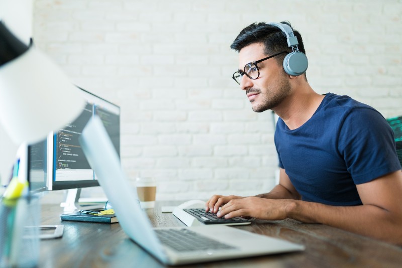 Handsome young male software developer programming codes while working from home-Developer to CTO