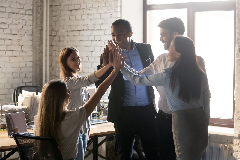 Happy excited multinational coworkers associates giving high five-Conscious Culture