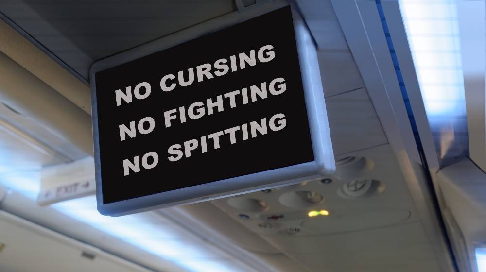 Humorous interior plane TV monitor message prohibiting passengers from rude and unruly behavior | Justice Department Will Charge Unruly Airline Passengers | featured