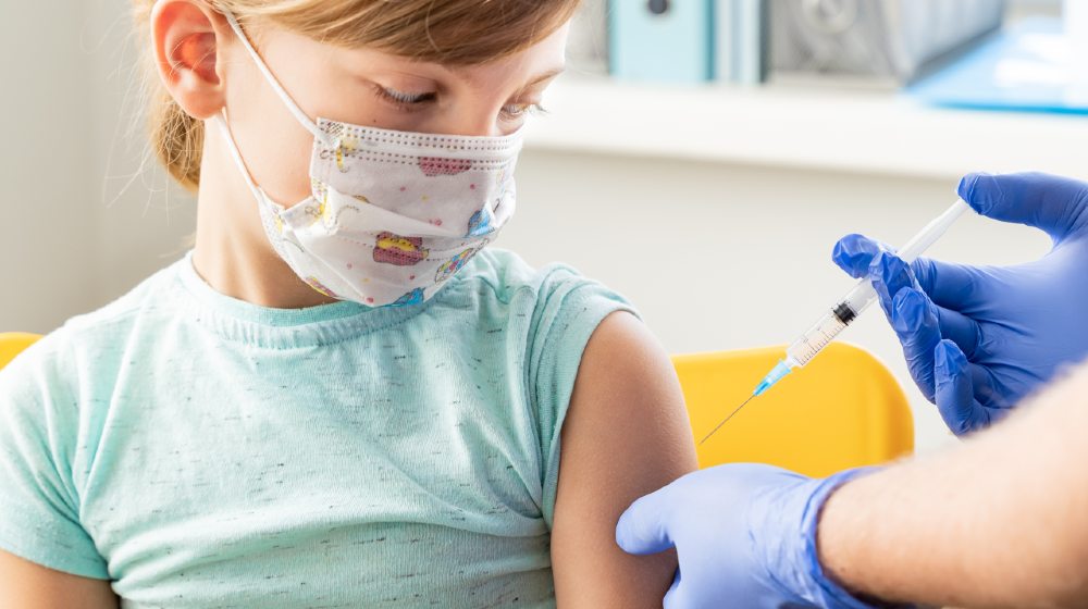 Little girl in face mask in doctor's office is vaccinated-COVID-19 Vaccines on Children-ss-featured | COVID-19 Vaccines on Children