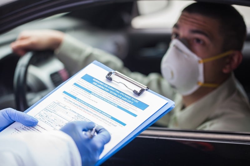Male driver wearing protective N95 face mask sitting by the wheel in drive-thru COVID-19 test centre-Vaccine Mandate Exemptions