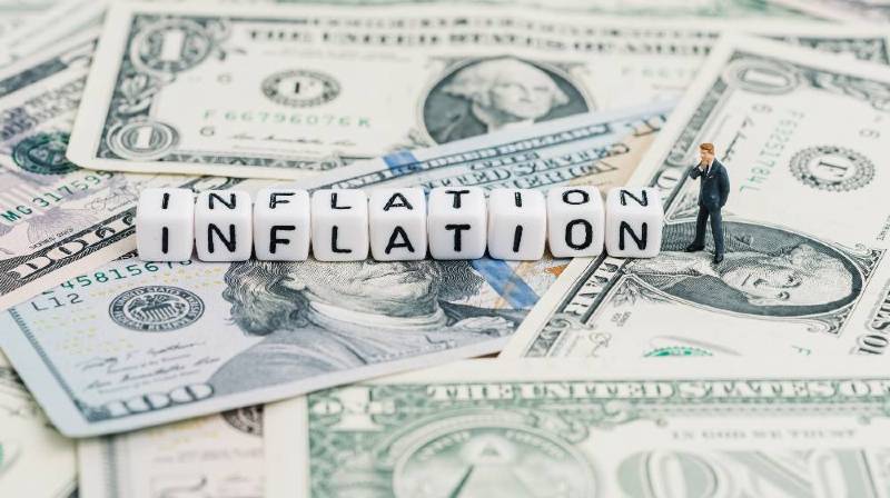 Miniature people businessman standing and wise thinking with cube block combine word Inflation on US dollar money banknote-Tudor Jones