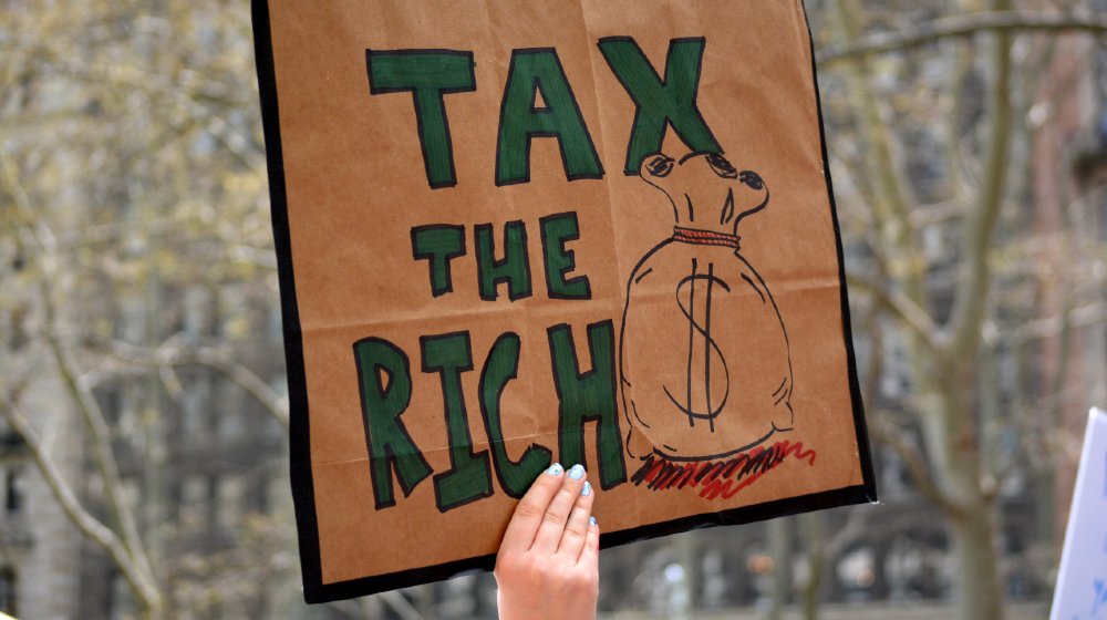 People carrying signs protesting President Trump at the Tax March in Manhattan in 2017 in New York City-Wealth Tax-ss-featured